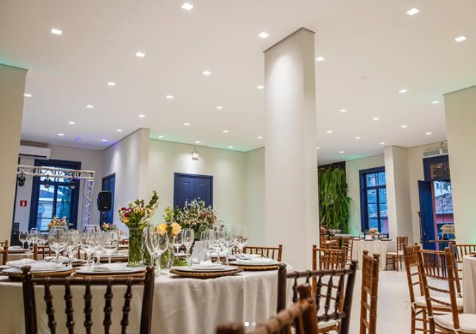 Salão montado com mesas postas para evento corporativo