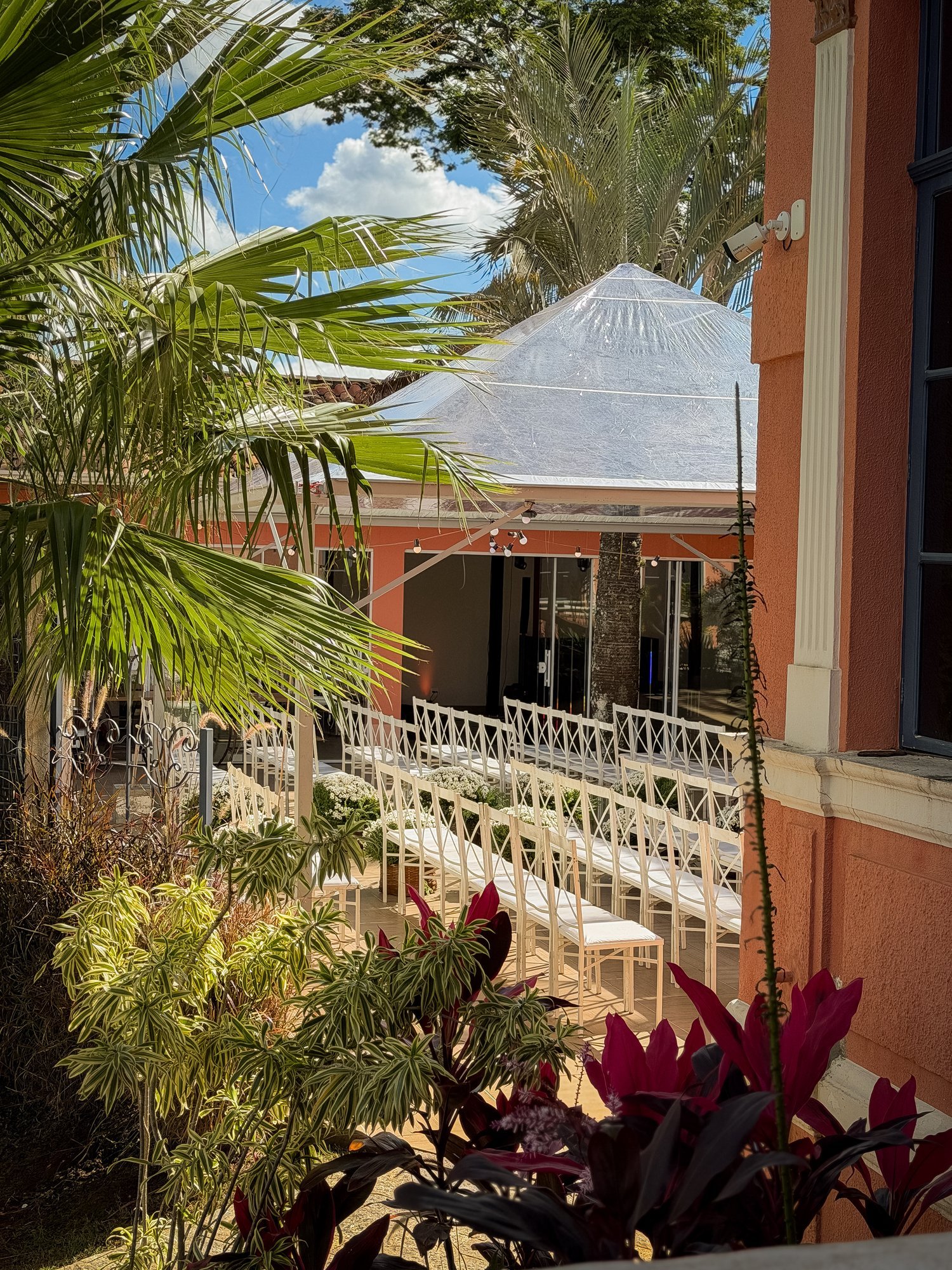 Pátio montado para cerimônia ao ar livre com cadeiras brancas