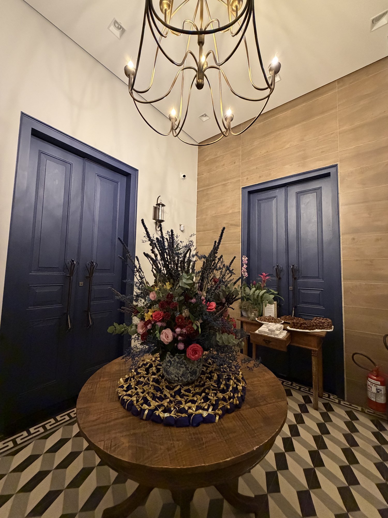 Hall de entrada com lustre dourado e arranjo floral central